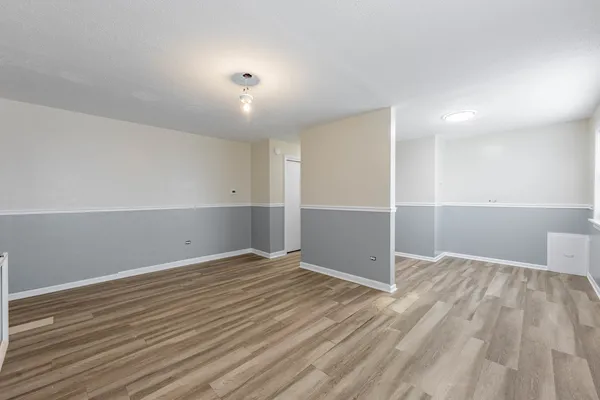 a view of an empty room with wooden floor and closet