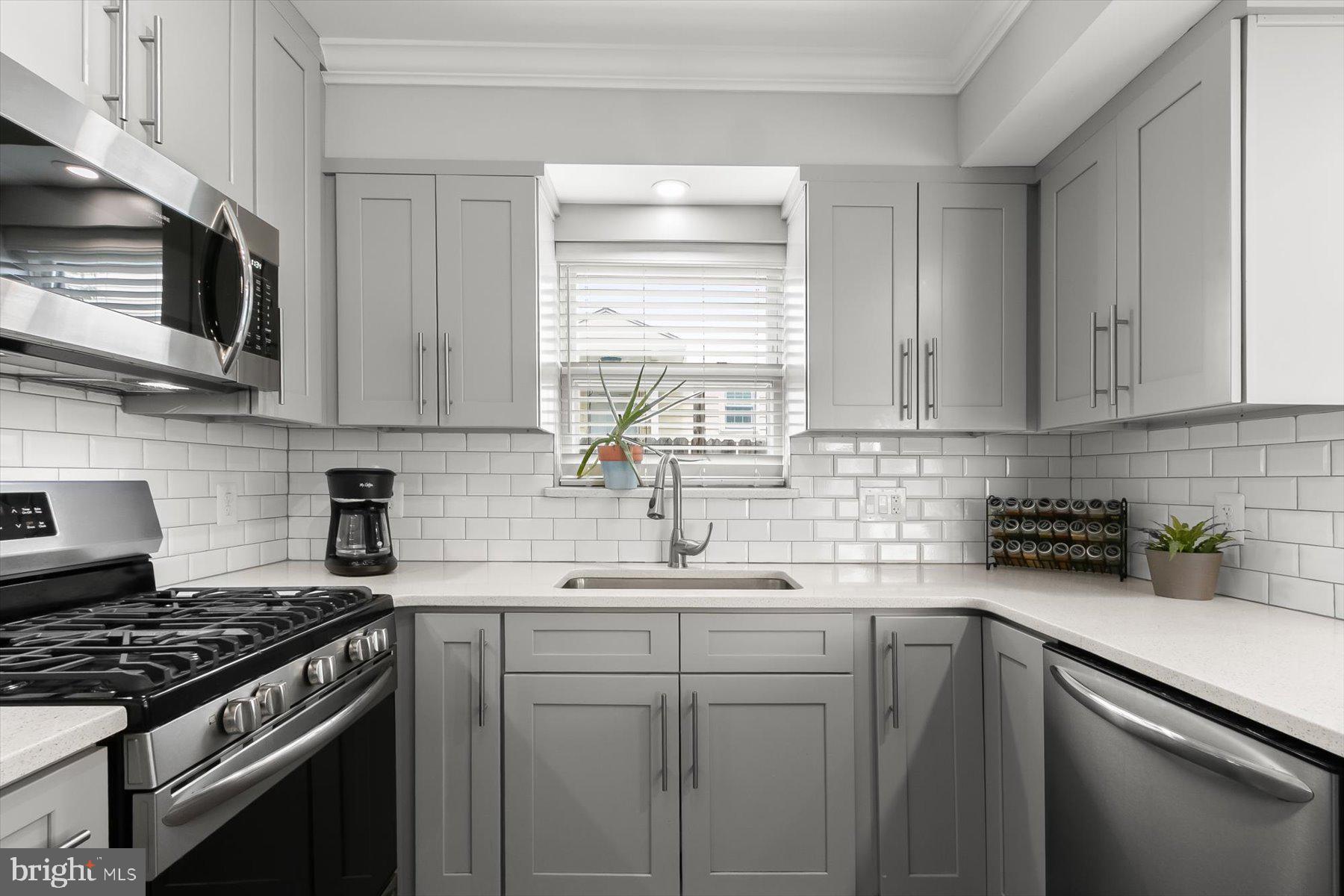 513 Gilmoure Drive Silver Spring, MD 20901 - Photo 16 of 60 a kitchen with stainless steel appliances a sink a stove a microwave and cabinets