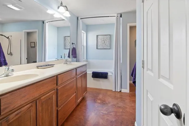 a spacious en suite bathroom with a sink a mirror a vanity and shower