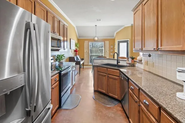 a kitchen with stainless steel appliances granite countertop a refrigerator a sink dishwasher a stove and white countertops with cabinets