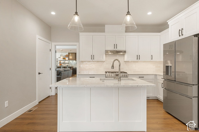 1192 East Ashdown Road Cedar City, UT 84721 - Photo 52 of 96 Kitchen featuring a central island with a solid surface countertop, white cabinetry with dark hardware, stainless steel appliances, wood-finish flooring, and pendant lighting