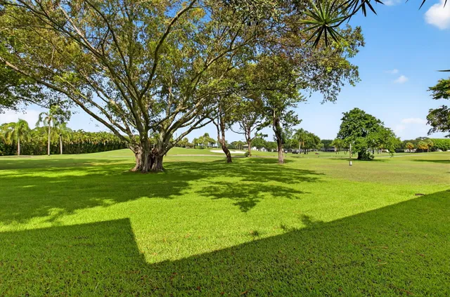 a view of grassy field with benches and trees all around
