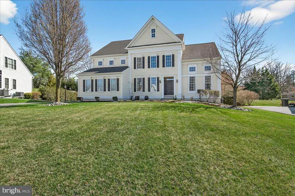 a front view of a house with a yard and trees
