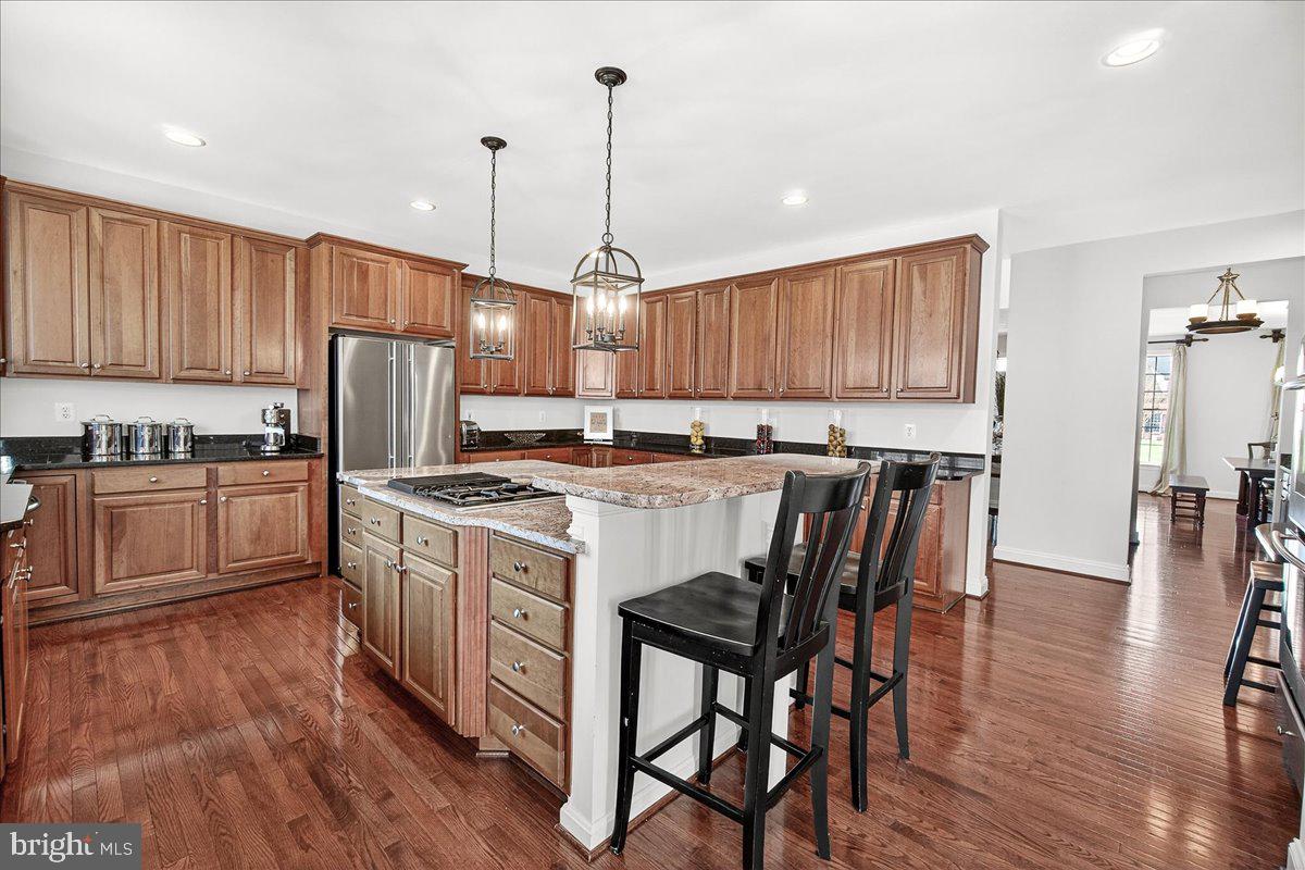 411 William Plummer Street New Market, MD 21774 - Photo 21 of 89 a kitchen with kitchen island granite countertop wooden floors white cabinets and appliances