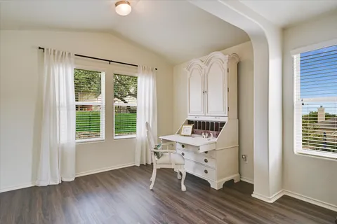 wooden floor in an empty room with a window and a kitchen