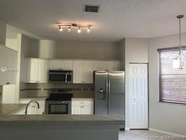 15751 Southwest 20th Street Miramar, FL 33027 - Photo 11 of 34 a kitchen with stainless steel appliances a refrigerator a stove a sink a chimney and a refrigerator