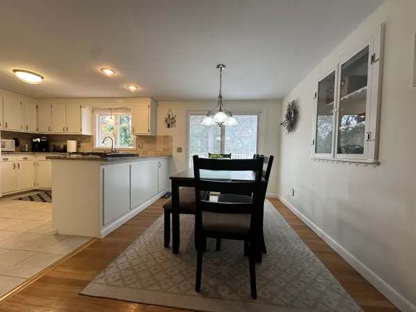a kitchen with stainless steel appliances granite countertop a stove a sink dishwasher a dining table and chairs with wooden floor