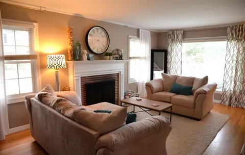 a living room with furniture a large window and a fireplace