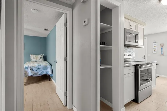 a hallway with white cabinets and stove