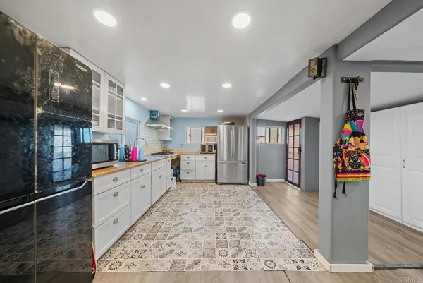 a large white kitchen with lots of clutter and stainless steel appliances