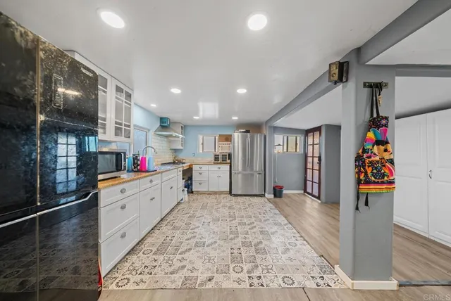 a large white kitchen with lots of clutter and stainless steel appliances