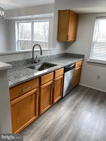 a kitchen with granite countertop wooden cabinets a sink and a window