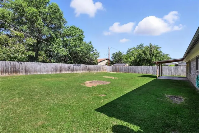 a view of yard with grass & fence