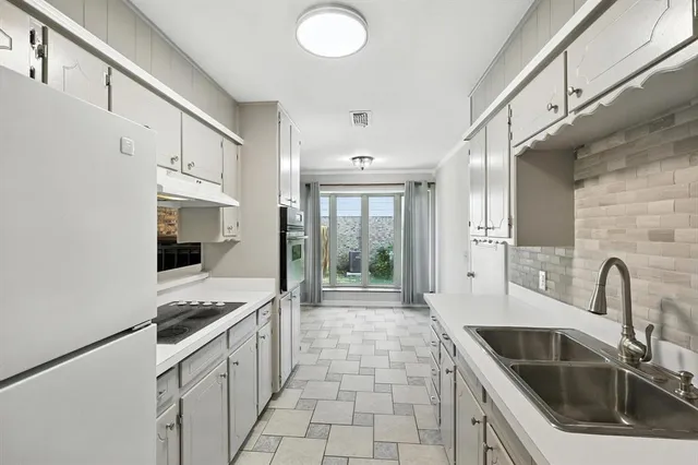 a kitchen with granite countertop a sink stove and refrigerator