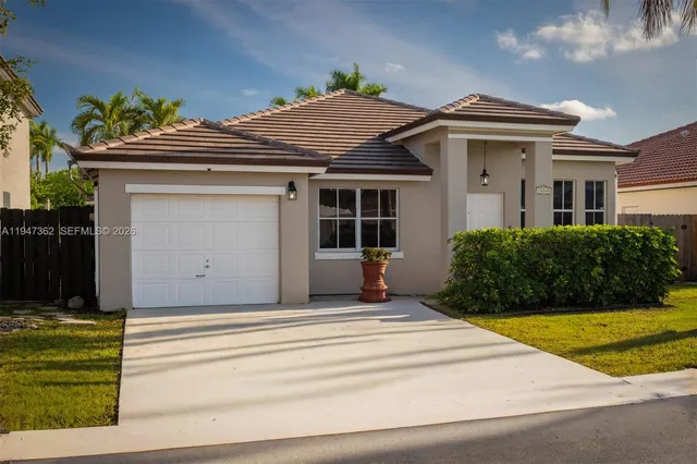a view of a house with a small yard plants and large tree