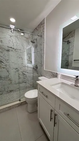a bathroom with a granite countertop sink toilet and shower