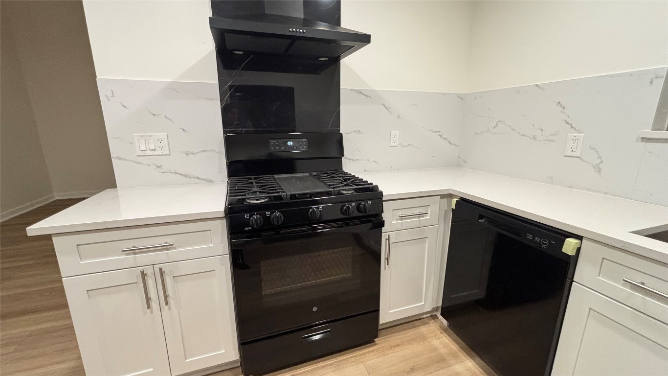 4507 Dorsett Oaks Circle, Unit A Austin, TX 78727 - Photo 5 of 26 Remodeled Kitchen featuring black appliances, light wood finished floors, wall chimney exhaust hood, and white cabinetry
