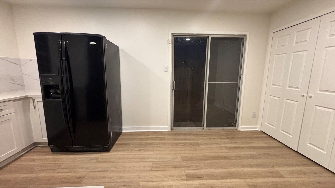 4507 Dorsett Oaks Circle, Unit A Austin, TX 78727 - Photo 6 of 26 Kitchen featuring black refrigerator with ice dispenser, light wood finished floors, white cabinetry, and light stone counters