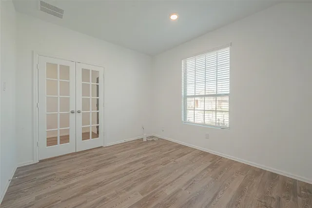 an empty room with wooden floor and windows