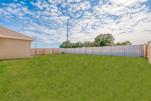 a view of yard with grass and wooden fence
