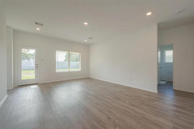 an empty room with wooden floor and windows