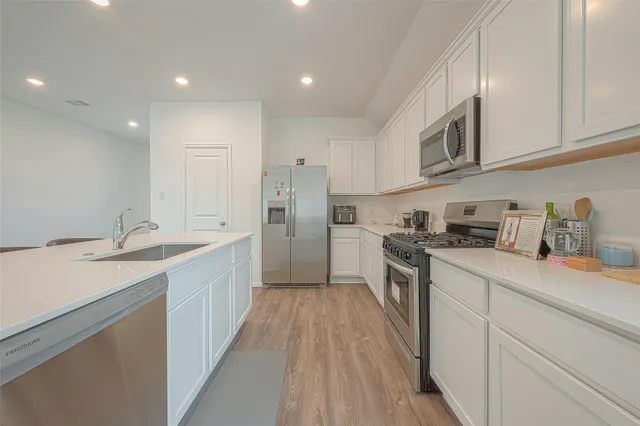 a kitchen with a sink dishwasher a refrigerator and a stove with wooden floors
