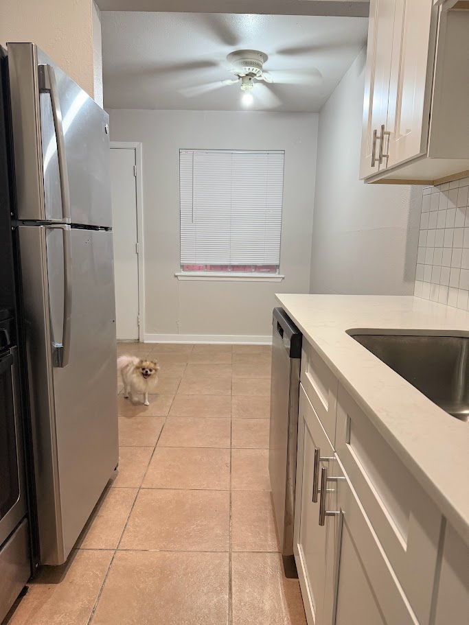 307 East 31st Street, Unit 106 Austin, TX 78705 - Photo 4 of 12 a kitchen with a sink a refrigerator and cabinets