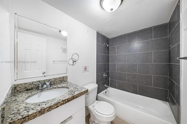 a bathroom with a granite countertop sink a toilet and bathtub