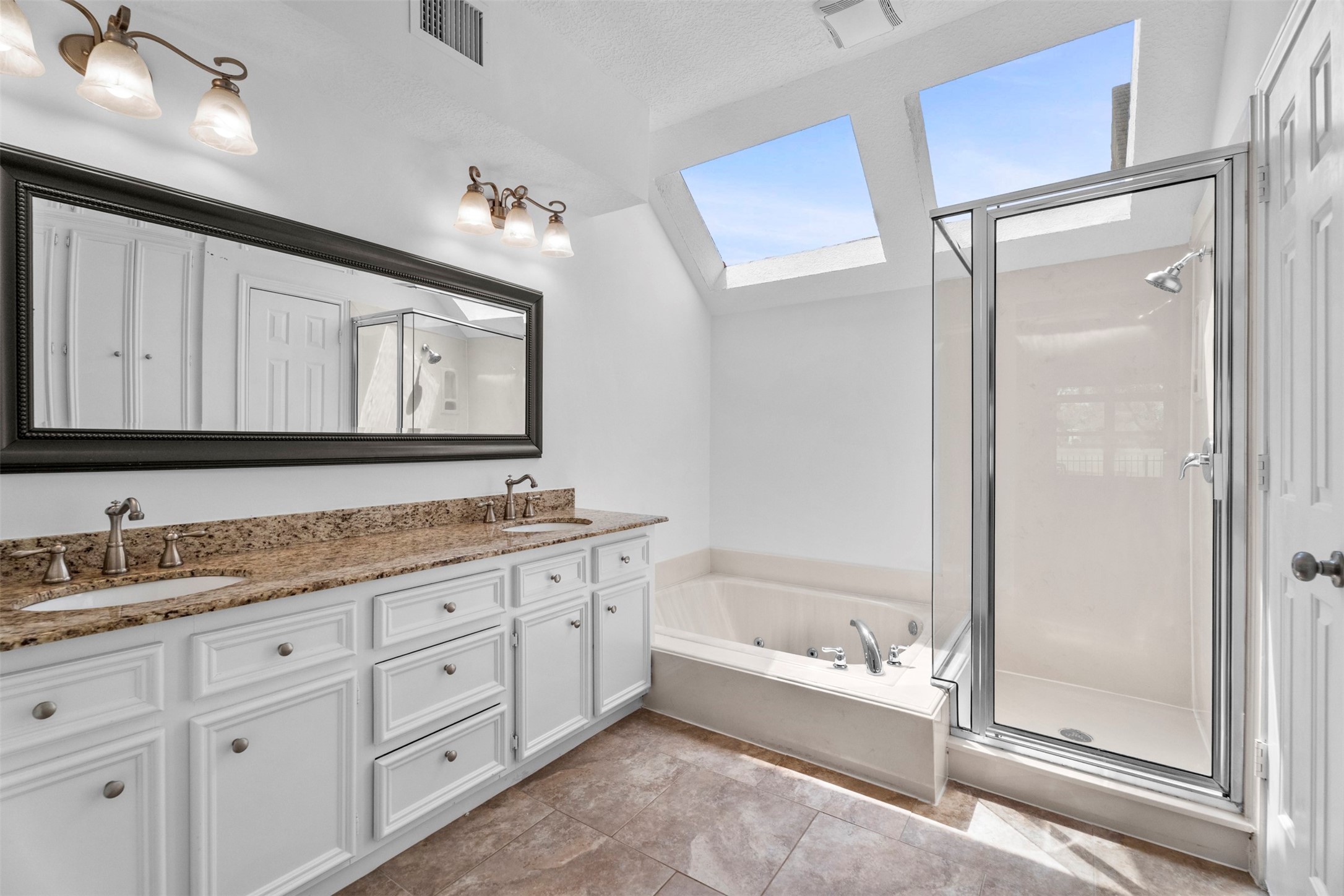 7635 Ameswood Road Houston, TX 77095 - Photo 22 of 39 Primary bedroom ensuite with jetted tub, separate shower and double sinks. The sky lights bring in tons of natural light.