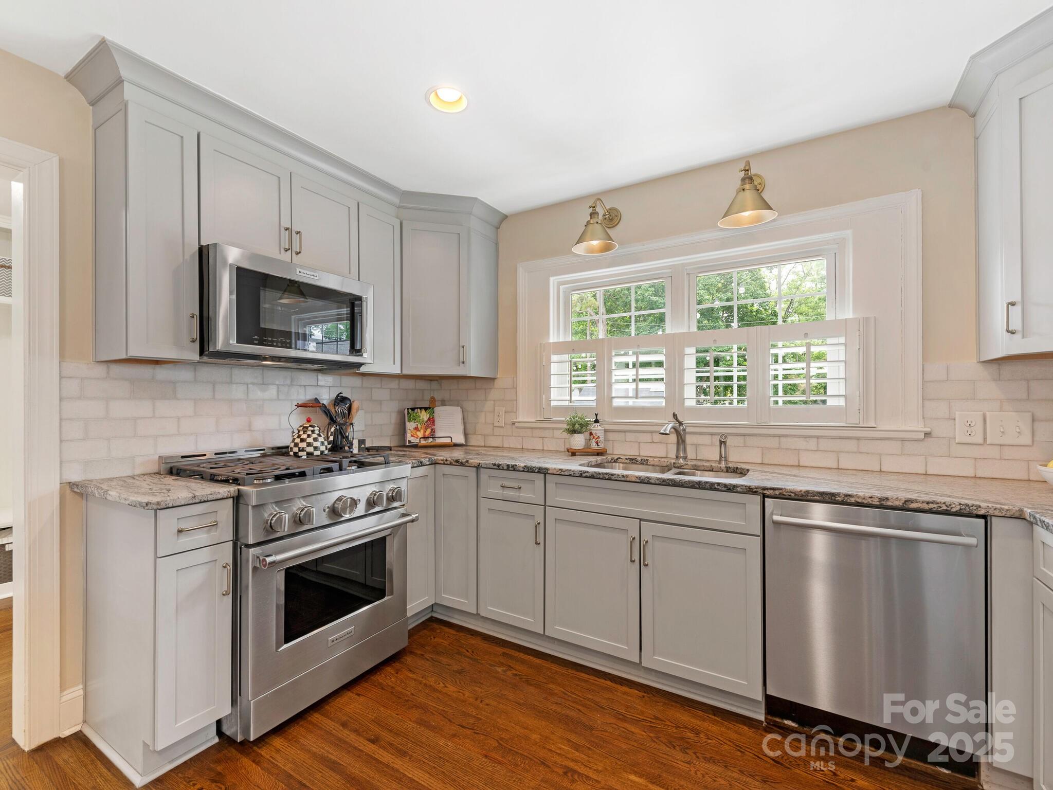 4346 Walker Road Charlotte, NC 28211 - Photo 10 of 30 a kitchen with granite countertop white cabinets a sink and a stove with wooden floor