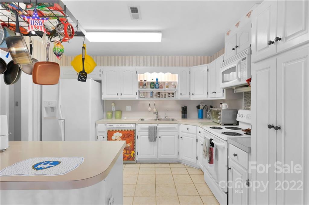 1414 Lighthouse Avenue Fort Mill, SC 29708 - Photo 12 of 47 a kitchen with stainless steel appliances granite countertop a sink a stove a chimney a refrigerator and white cabinets with wooden floor