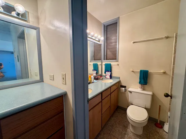 a bathroom with a granite countertop toilet sink and mirror