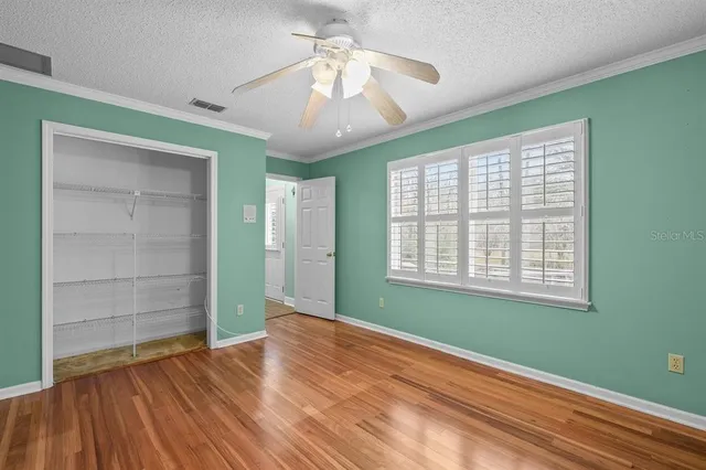a view of an empty room with a window and wooden floor
