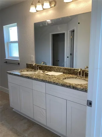 a bathroom with a granite countertop sink and a mirror