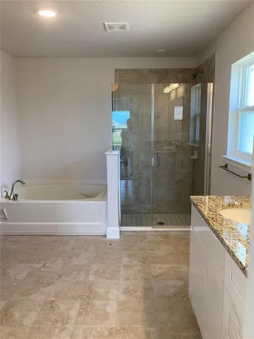 a bathroom with a granite countertop bathtub and a shower