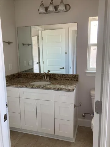 a bathroom with a granite countertop sink and a toilet