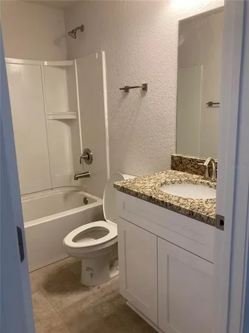 a bathroom with a granite countertop toilet sink and mirror