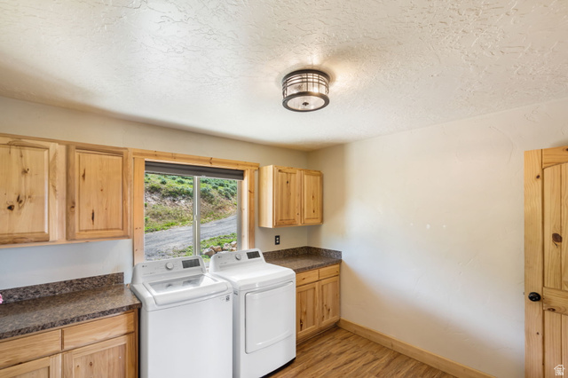 2013 North River View Road Huntsville, UT 84317 - Photo 35 of 53 Laundry room with light wood-style floors, washing machine and clothes dryer, cabinet space, and a textured ceiling