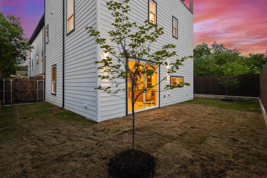 415 North Patton Avenue Dallas, TX 75203 - Photo 19 of 20 The property features a private yard with a young tree, white siding, and a large sliding glass door