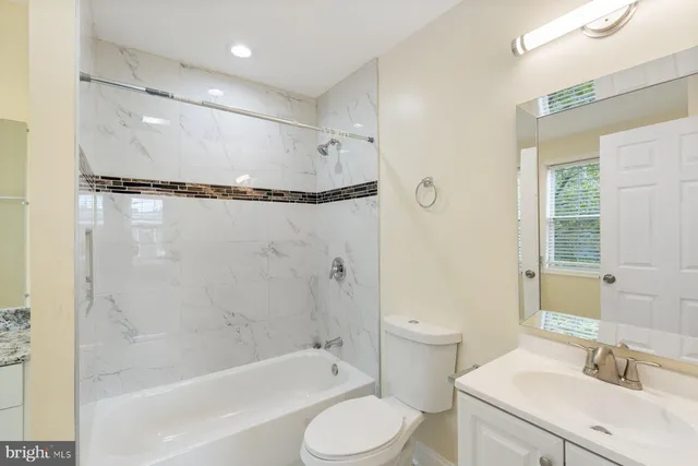a bathroom with a granite countertop sink a toilet and a bathtub