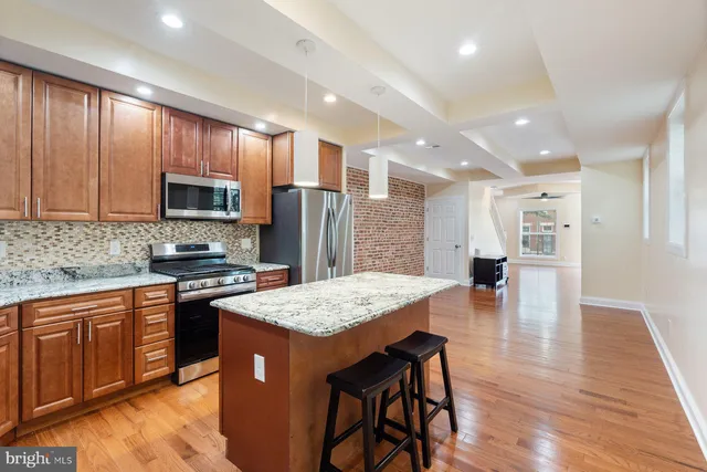 a kitchen with stainless steel appliances granite countertop a refrigerator a sink dishwasher and a stove with wooden floors