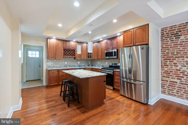 a kitchen with stainless steel appliances granite countertop a refrigerator a sink a stove and island