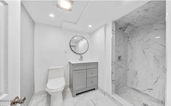 a bathroom with a toilet a sink a mirror and a shower