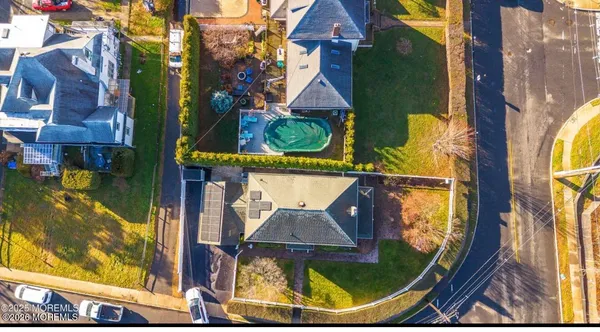 an aerial view of a residential houses with outdoor space and a street view