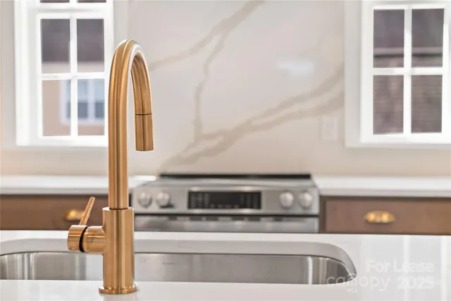 a kitchen with stainless steel appliances granite countertop a sink a stove a refrigerator and a dining table with wooden floor