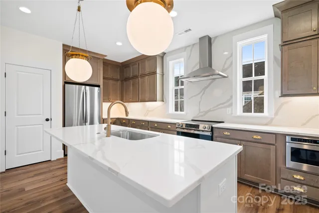 a kitchen with stainless steel appliances granite countertop a sink a stove and a wooden cabinets