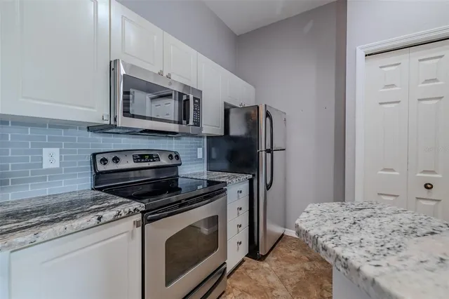 a kitchen with stainless steel appliances granite countertop a stove refrigerator and a microwave oven