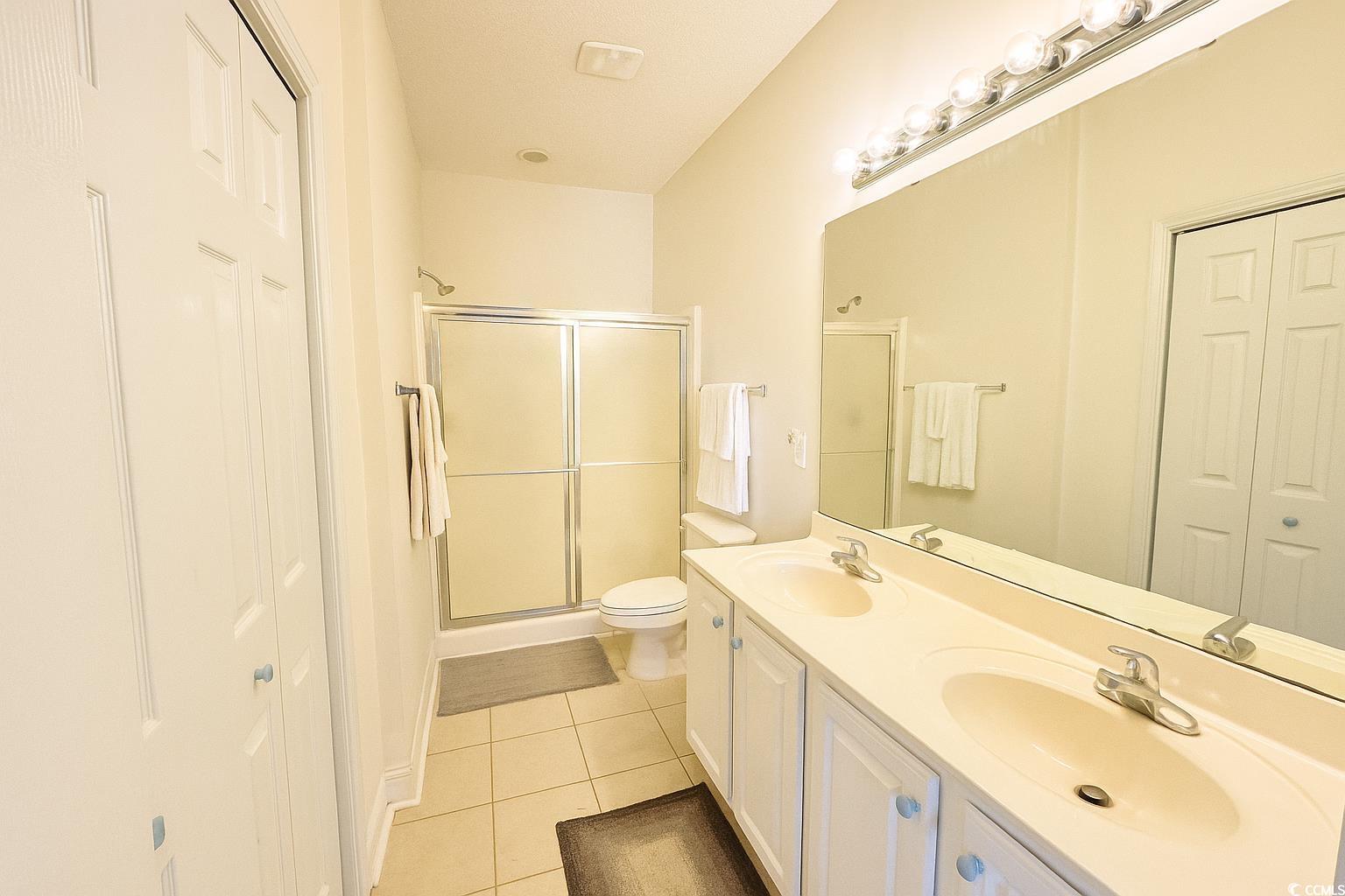 1100 Commons Boulevard, Unit 508 Myrtle Beach, SC 29572 - Photo 13 of 24 Full bath featuring a closet, light tile patterned flooring, double vanity, and a stall shower