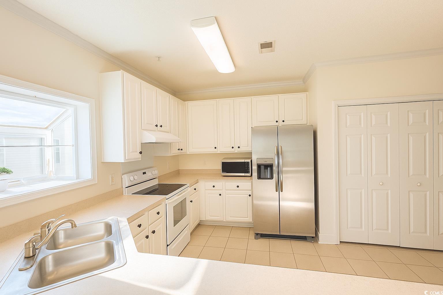 1100 Commons Boulevard, Unit 508 Myrtle Beach, SC 29572 - Photo 8 of 24 Kitchen with stainless steel appliances, light countertops, white cabinetry, light tile patterned floors, and crown molding