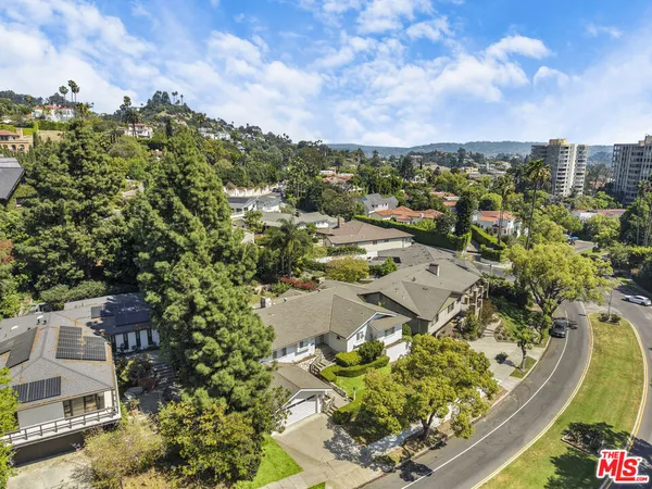 an aerial view of residential house with outdoor space and trees all around